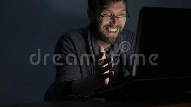 在笔记本电脑上工作的长胡子男人非常开心，开始感到非常惊讶和不安